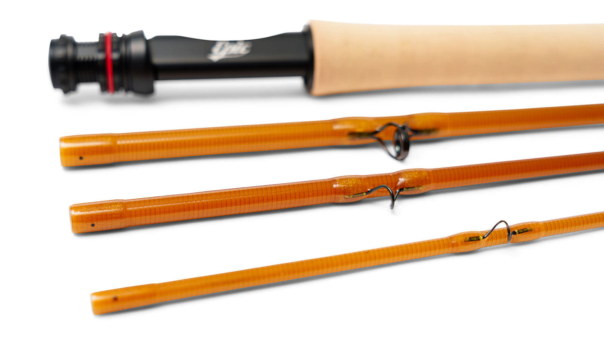 Close-up of a fly fishing rod shown disassembled on a clean white background. The rod features a natural cork handle, and black guides.